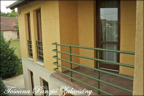 a balcony of a house with green railing at Toscana Panzió in Zalacsány