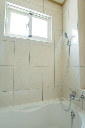 a shower in a bathroom with a tub and a window at Bai Shengcun Homestay in Guoxing