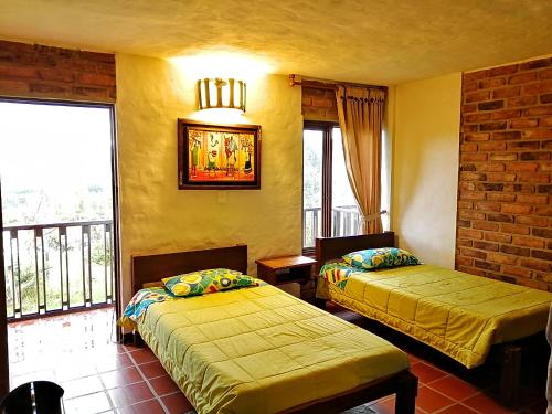 a room with two beds and a window with a balcony at Posada San Esteban in Sutamarchán