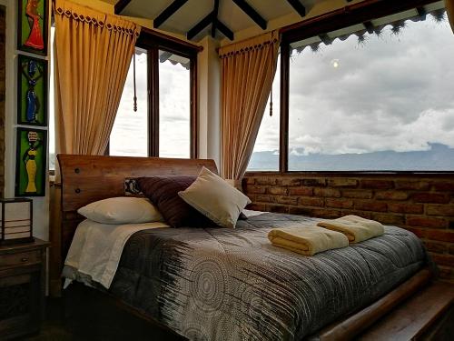 a bedroom with a bed with a large window at Posada San Esteban in Sutamarchán