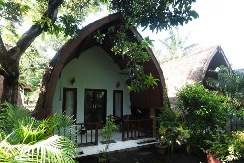 a small house with an arched doorway in a garden at Ina Gili Guesthouse in Gili Air