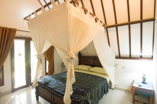 a bedroom with a canopy bed with curtains at Ina Gili Guesthouse in Gili Air
