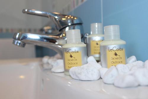 a bathroom sink with three bottles of soap and towels at Hotel Palinuro in Palinuro