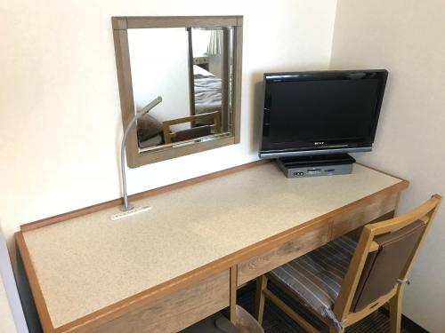 einen Schreibtisch mit einem TV und einem Spiegel in der Unterkunft Ichinomiya Green Hotel in Ichinomiya