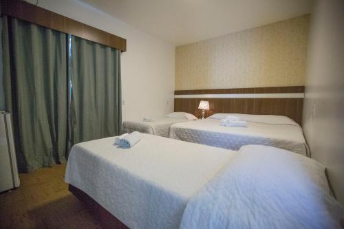 a hotel room with two beds and a window at Hotel Vivere Cataratas in Foz do Iguaçu