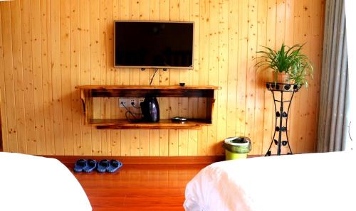 a room with a television on a wooden wall at Tongfu Inn(In the National Park) in Zhangjiajie
