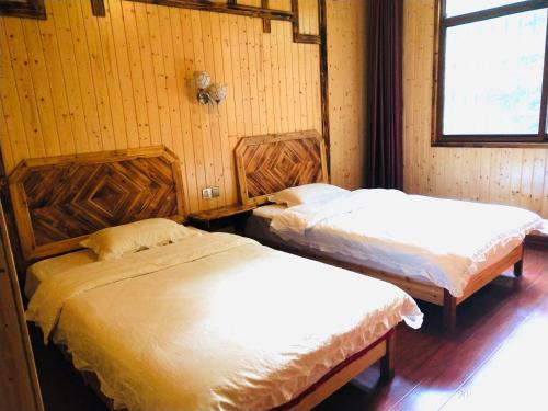 two beds in a room with wooden walls at Tongfu Inn(In the National Park) in Zhangjiajie