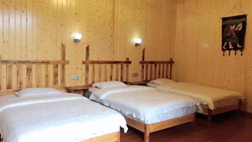 three beds in a room with wooden walls at Tongfu Inn(In the National Park) in Zhangjiajie