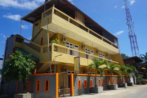 a large yellow building with trees in front of it at Orange Hotel in Labuan Bajo