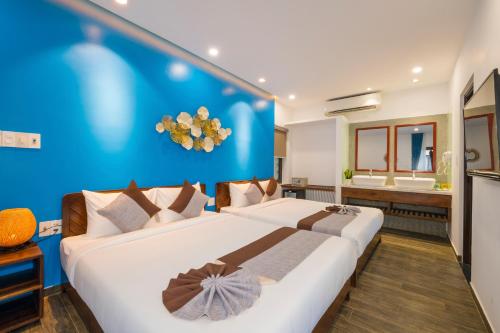 two beds in a room with a blue wall at December Hoi An Villa in Hoi An