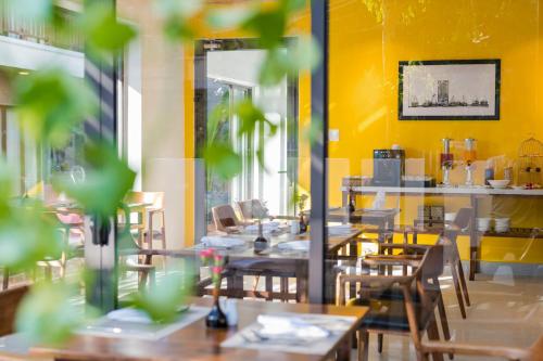 a restaurant with wooden tables and chairs and yellow walls at December Hoi An Villa in Hoi An