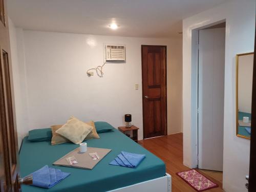 1 dormitorio con 1 cama con manta azul y mesa en Raje Residence, en El Nido