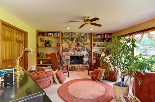 a living room with a stone fireplace and a ceiling fan at Arborhouse **** Naperville-Lisle in Lisle