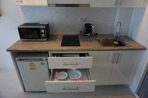 a small kitchen with a sink and a microwave at Grandblue Condominium#702 Seaview TopFloor MaePhim Rayong in Mae Pim
