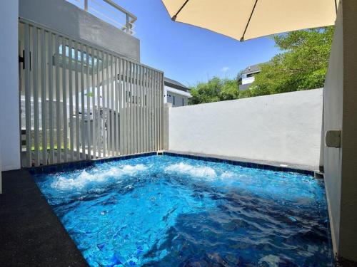 a swimming pool in the floor of a house with an umbrella at Plumeria Luxury Service Villa in George Town