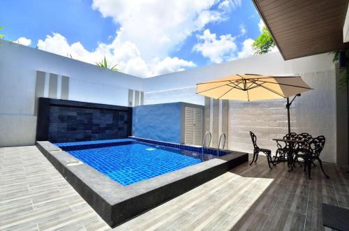 uma piscina com uma mesa e cadeiras e um guarda-sol em Violet Luxury Service Villa em Batu Ferringhi