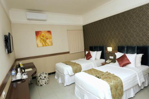 a hotel room with two beds and a television at Amarelo Hotel Solo in Solo
