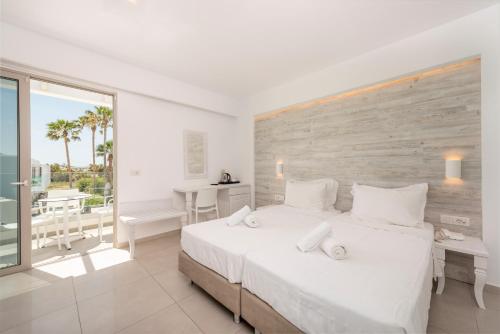 a white bedroom with a large bed and a balcony at Apollon Windmill Boutique Hotel - Adults Only in Kos
