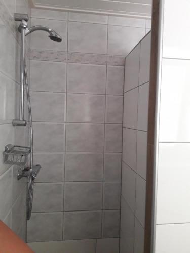 La salle de bains est pourvue d'une douche et de carrelage blanc. dans l'établissement Erlebnishof Schiman, à Kirchbach
