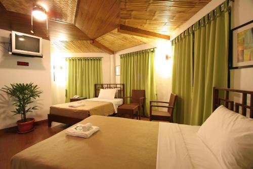 a hotel room with two beds and green curtains at Coron Hilltop View Resort in Coron