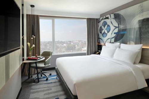 a hotel room with a large bed and a desk at Novotel Suites Yogyakarta Malioboro in Yogyakarta