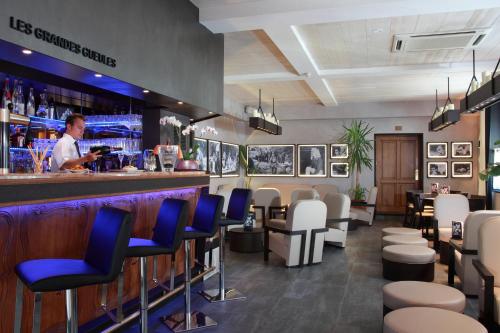 a bar with blue chairs and a man behind the counter at Hotel de la Jamagne & Spa in Gérardmer