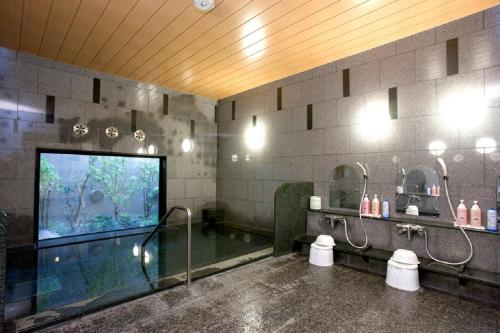 a bathroom with a shower and a large screen television at Hotel Route-Inn Nobeoka Ekimae in Nobeoka