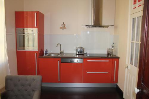 kuchnia z czerwonymi szafkami i zlewem w obiekcie Les Bruyères w mieście Les Sables-dʼOlonne