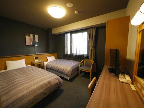 a hotel room with two beds and a television at Hotel Route-Inn Sapporo Kitayojo in Sapporo