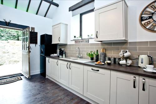 a kitchen with white cabinets and a clock on the wall at The Barn in Lanhydrock, Bodmin in Bodmin
