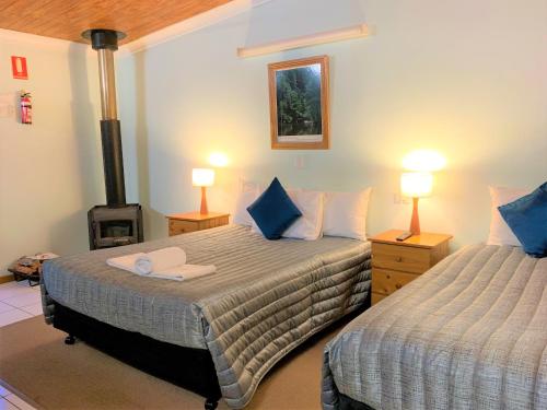 a bedroom with two beds and a fireplace with two lamps at Broken River Mountain Resort in Eungella