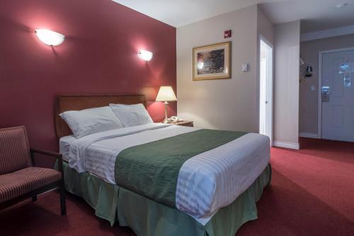 a hotel room with a large bed and a chair at Port Augusta Inn in Comox
