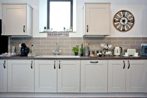 a kitchen with white cabinets and a clock on the wall at The Barn in Lanhydrock, Bodmin in Bodmin