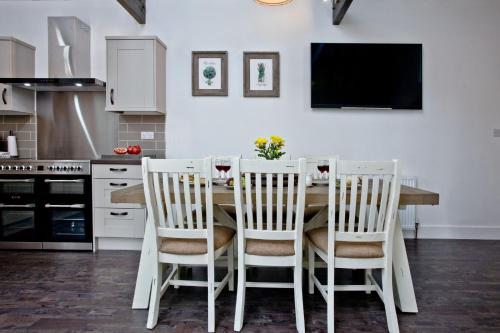a kitchen with a table with chairs and a tv at The Barn in Lanhydrock, Bodmin in Bodmin