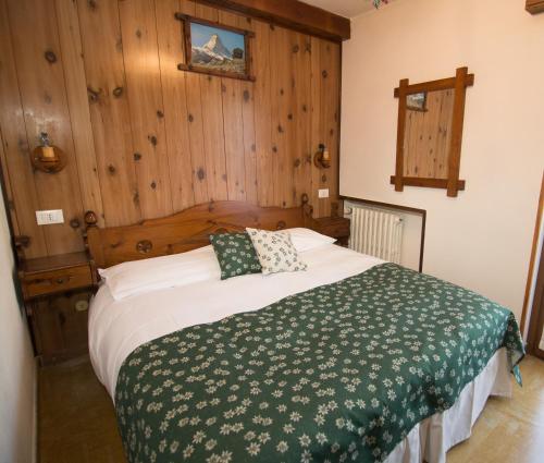 a bedroom with a bed with a green and white blanket at Hotel Edelweiss in Limone Piemonte