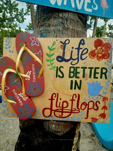 a sign that says life is better in flipops on a tree at Bolo Beach Santorini nearby to Hundred Island in Alaminos
