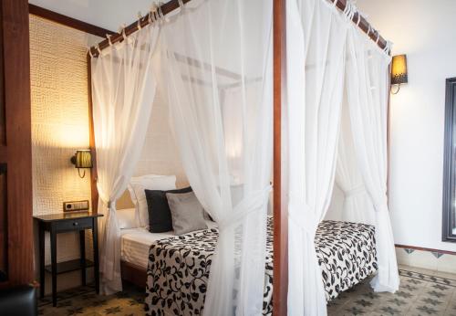 a bedroom with a canopy bed with white curtains at Hostal Palacio San Bartolomé in El Puerto de Santa María