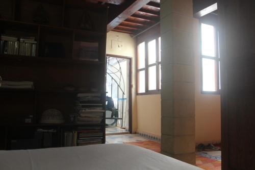 um quarto com duas janelas e uma estante de livros em zazou em Essaouira