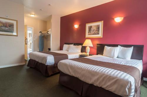 two beds in a hotel room with purple walls at Port Augusta Inn in Comox