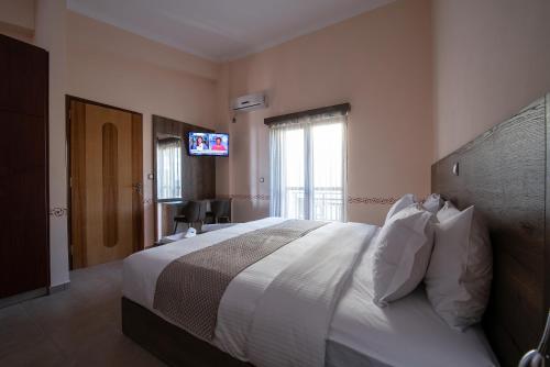 a bedroom with a large white bed and a television at Cyrenia Guesthouse in Monemvasia