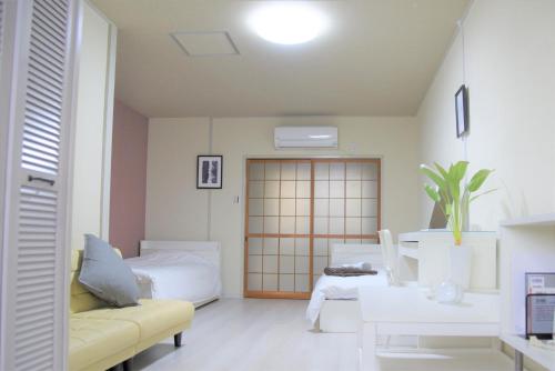 Osaka U-Shuku في أوساكا: غرفة معيشة بها أريكة صفراء وأثاث أبيض