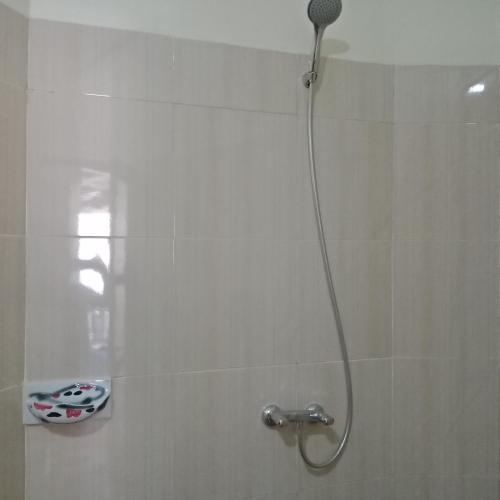 a shower with a shower head in a bathroom at Backpackers Home Amed in Amed