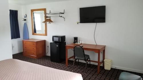 a room with a desk with a computer and a television at Budget Inn Breezewood in Breezewood