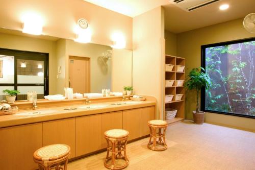 a bathroom with a large mirror and two sinks and stools at Hotel Route-Inn Yatsushiro in Yatsushiro