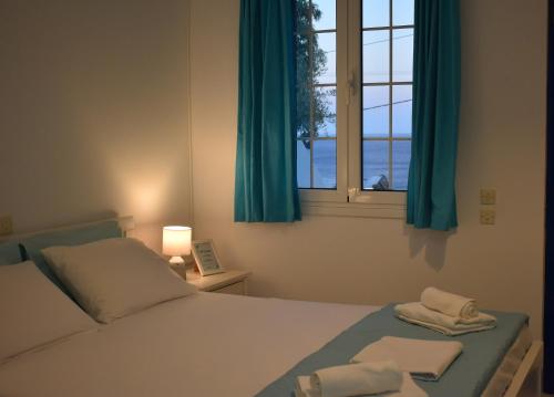 a bedroom with a bed and a window with blue curtains at Litus Studios Syros in Megas Yialos-Nites