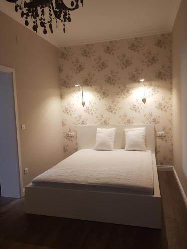 a bedroom with a white bed with a floral wallpaper at Apartments Lorenco in Tisno