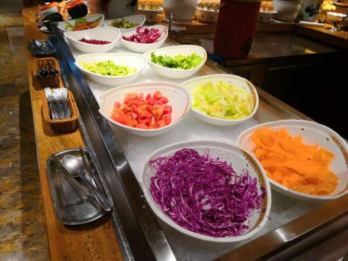 a buffet with bowls of vegetables on a counter at San Po Hotel - Fuzhou Pushang in Fuzhou
