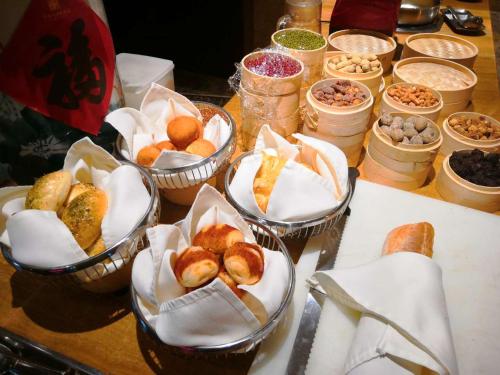 a table topped with bowls of pastries and other foods at San Po Hotel - Fuzhou Pushang in Fuzhou