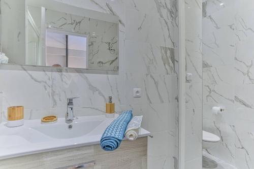 une salle de bain blanche avec un lavabo et un miroir dans l'établissement Maison Bianchi - 45 Berlioz, à Nice