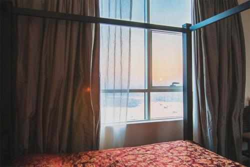 a bedroom with a bed and a large window at Exclusive Creek Bay Apartment in Ajman 
